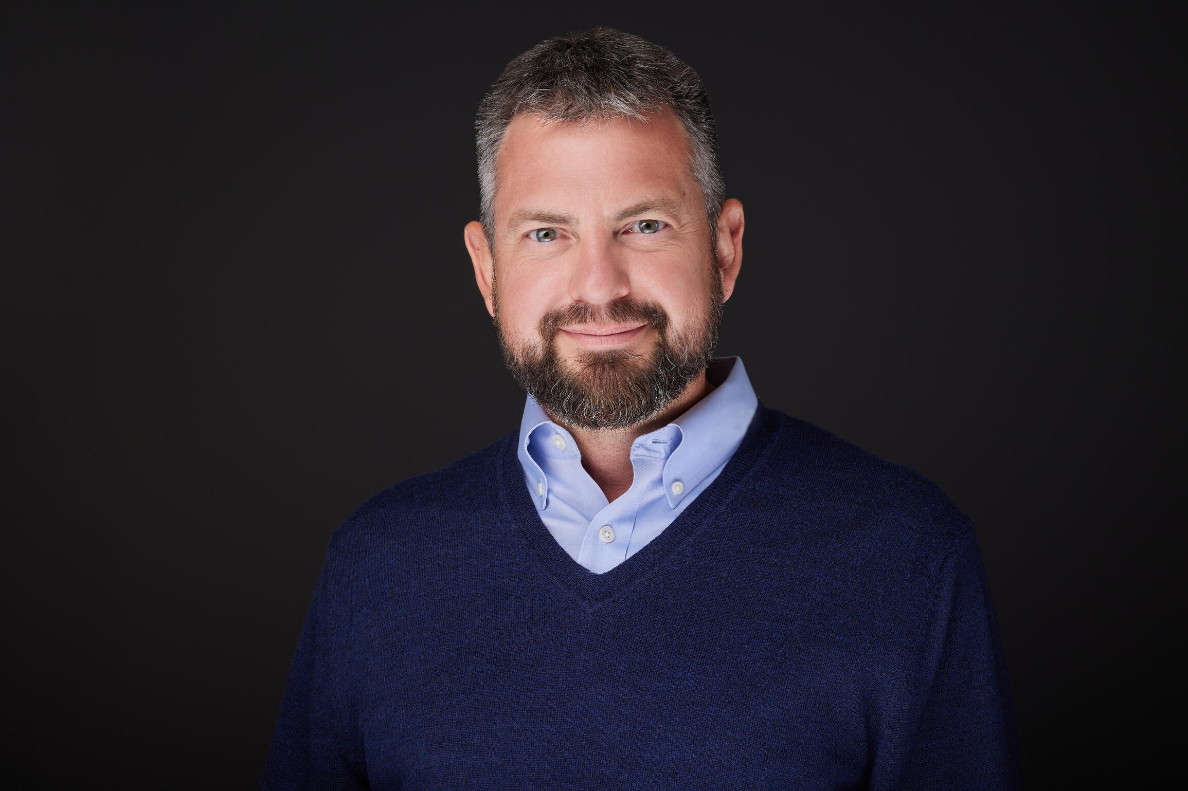 A picture of Mike Boyer wearing a blue sweatshit and smiling.